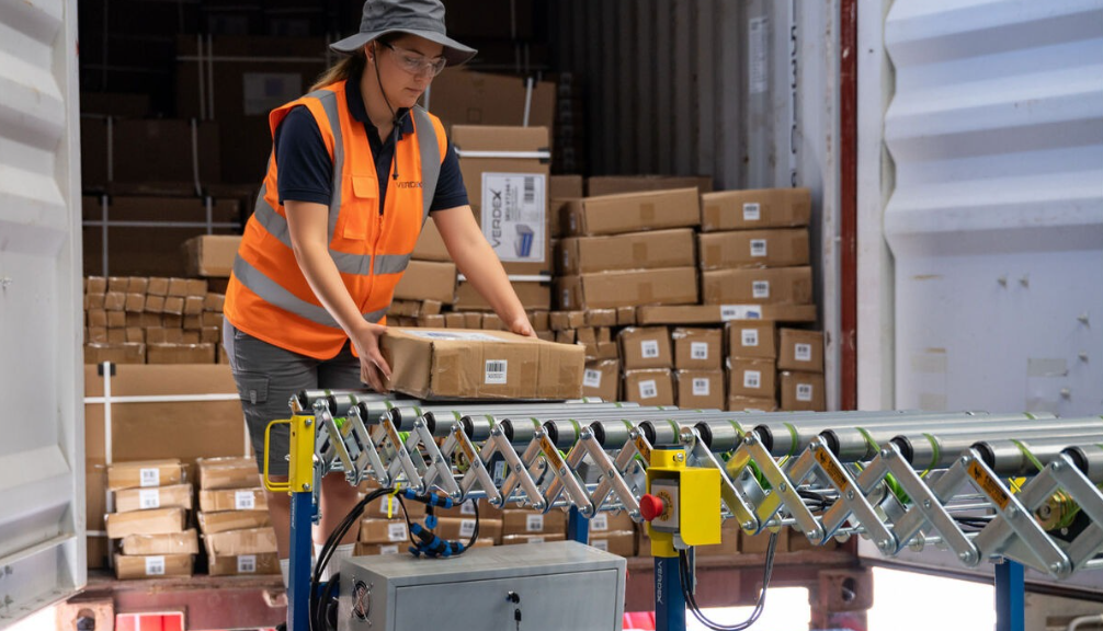 Female Warehouse Retail Specialist Placing Boxes Electric Expandable Conveyors