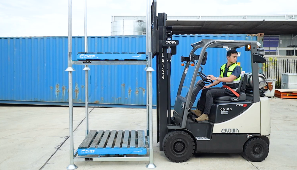 Forklift Driver Demonstrating Stackable Stillage Cage Feature In Back Loading Dock